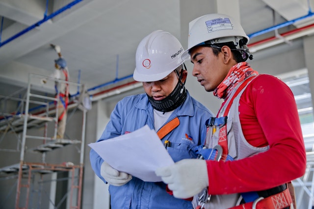 Two men looking at papers at a construction site. 